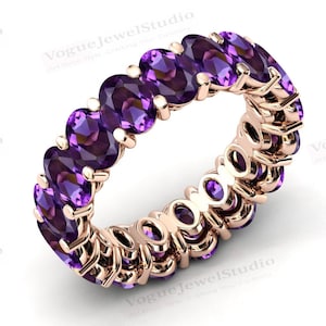 May include: A rose gold eternity band with a row of oval-shaped amethyst gemstones.