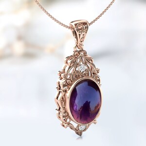 May include: A delicate rose gold pendant necklace features an oval amethyst gemstone surrounded by a filigree design with smaller clear gemstones.