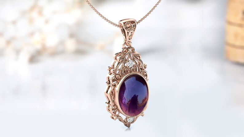 May include: A delicate rose gold pendant necklace features an oval amethyst gemstone surrounded by a filigree design with smaller clear gemstones.