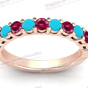 Puede incluir: Un anillo de banda de oro rosa con piedras turquesa y rubí alternas.