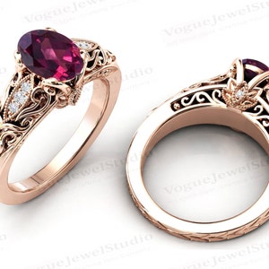 May include: A rose gold engagement ring with an oval-shaped pink gemstone and a filigree design. The ring is set with smaller diamonds on the band.