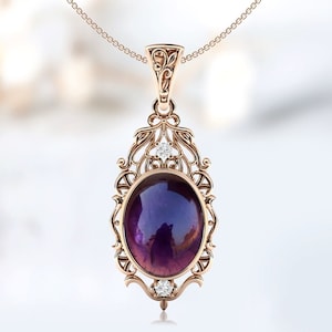 May include: A delicate rose gold pendant necklace features an oval amethyst gemstone surrounded by a filigree design. Two small diamonds accent the top and bottom of the pendant.