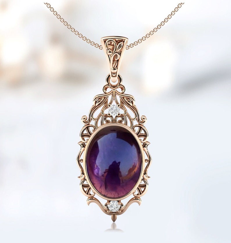 May include: A delicate rose gold pendant necklace features an oval amethyst gemstone surrounded by a filigree design. Two small diamonds accent the top and bottom of the pendant.