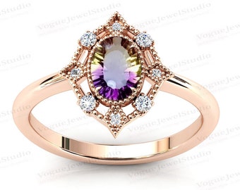 Puede incluir: Un anillo de oro rosa con una gran piedra preciosa ovalada engastada en un delicado diseño de filigrana. La piedra preciosa es una piedra multicolor, degradada con tonos de verde, morado y amarillo.