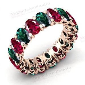Puede incluir: Un anillo de banda de oro con piedras ovaladas alternando verde esmeralda y rojo rubí.