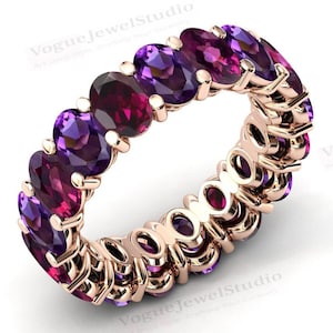 May include: A rose gold eternity band ring with alternating purple and pink oval-shaped gemstones.