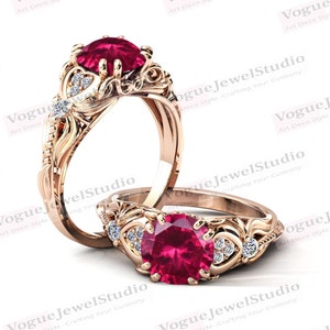 May include: Two gold rings with a red gemstone and small white gemstones. The rings have a detailed, ornate design.