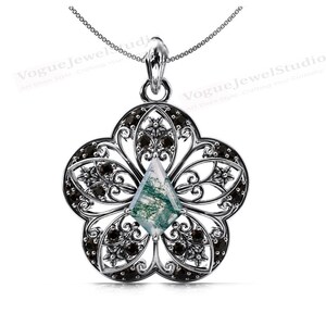 Op de afbeelding: Een zilveren ketting met een hanger met een groene agaat edelsteen in een diamantvorm, omgeven door een filigraan ontwerp in zilver met zwarte accenten.