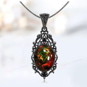 Könnte beinhalten: Schwarze Halskette mit Anhänger, der einen ovalen Opal-Edelstein in einem filigranen Design fasst. Der Opal hat eine rote, grüne und goldene Farbe. Der Anhänger ist mit schwarzen Diamanten verziert.