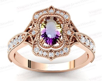 Puede incluir: Anillo de oro rosa con una piedra preciosa ovalada multicolor rodeada de pequeños diamantes redondos. El anillo tiene intrincados detalles de filigrana y diamantes adicionales en la banda. Diseño de inspiración vintage.