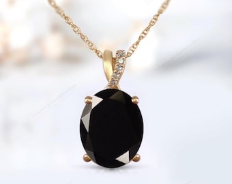 Pode incluir: Um colar de corrente de ouro com um pingente de pedra oval preta acentuado com pequenos diamantes. O pingente apresenta um design torcido.