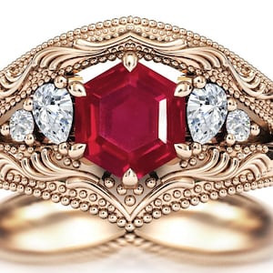 May include: A rose gold engagement ring featuring a large, hexagonal ruby gemstone surrounded by three smaller, pear-shaped diamonds.