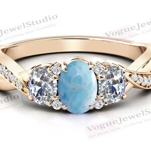 May include: A gold ring featuring a blue oval gemstone surrounded by smaller diamonds. The ring has a twisted band with diamonds set along the sides.