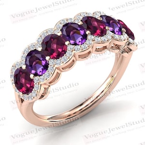May include: A rose gold band ring with five oval-shaped gemstones. The gemstones alternate between purple and pink. Each gemstone is surrounded by a halo of smaller diamonds.