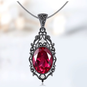 May include: Black pendant necklace with a large oval ruby gemstone surrounded by a filigree design and two smaller white gemstones.