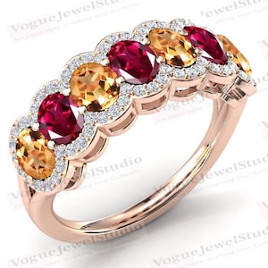 Può includere: Un anello a fascia in oro rosa con cinque pietre ovali. Le pietre sono incastonate in un alone di pietre rotonde più piccole. L'anello presenta pietre rosse e arancioni alternate.