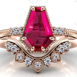 Puede incluir: Un anillo de compromiso de oro rosa con una gran piedra preciosa facetada de color rosa intenso y piedras preciosas más pequeñas de color claro. El anillo tiene un diseño delicado y ornamentado.