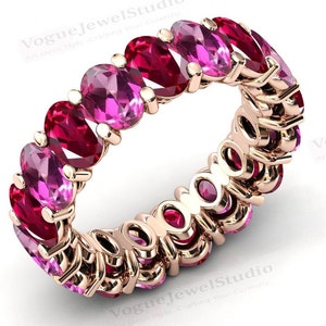 Könnte beinhalten: Ein Ewigkeitsring aus Roségold mit abwechselnd rosa und roten ovalen Edelsteinen.