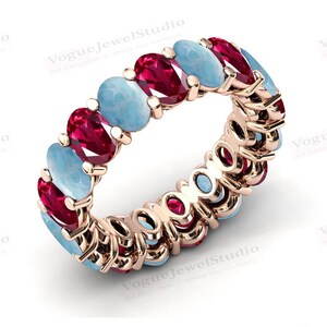 Puede incluir: Un anillo de eternidad de oro rosa con piedras preciosas ovaladas alternas de aguamarina y rubí.