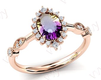 Puede incluir: Un anillo de oro rosa con una gran piedra preciosa ovalada rodeada por un halo de diamantes más pequeños. La piedra preciosa es una amatista multicolor con tonos de morado, verde y amarillo.