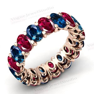 May include: A gold band ring with alternating blue and red oval gemstones. The ring is set with a total of 12 gemstones.