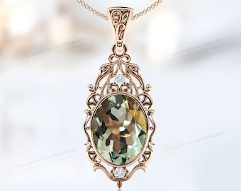 Può includere: Una collana con un ciondolo in oro rosa con una pietra preziosa ovale verde circondata da un delicato design a filigrana. Due piccoli diamanti adornano la pietra preziosa.