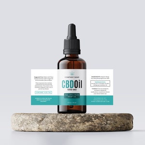 May include: A brown glass bottle of CBD oil with a black dropper top, labeled with the text "CBD Oil 1000 MG" and "Full Spectrum Hemp Oil." The label also includes a teal stripe and a cannabis leaf graphic. The bottle sits on a stone.