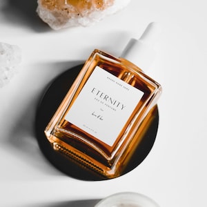 May include: A clear glass bottle of perfume with a white label that reads "Eternity Eau de Perfume for him & her 60 ml - 2 fl oz" and "Brand Name Here".