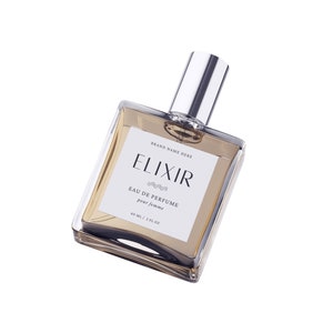 May include: A clear glass bottle of perfume with a silver cap. The label reads "Elixir Eau de Perfume pour femme 60 ml / 2 fl oz" and "Brand Name Here".