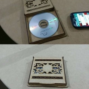 May include: A wooden box with a decorative cutout design. The box is open and a CD is visible inside. The CD has a white label with the text "MASTERPIECE" printed on it.