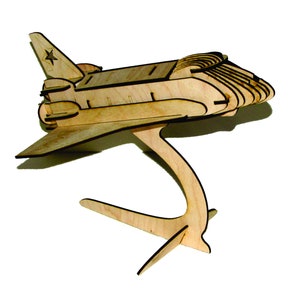 May include: A wooden model of a space shuttle with a star on the tail. The shuttle is on a stand with three legs.