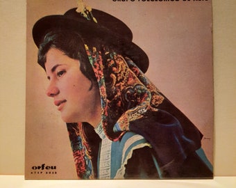 May include: A vintage record album cover featuring a woman wearing a colorful headscarf and a black hat. The album is titled "Grupo Folclórico de Alte" and the record label is "Orfeu" with the number "ATEP 6038".