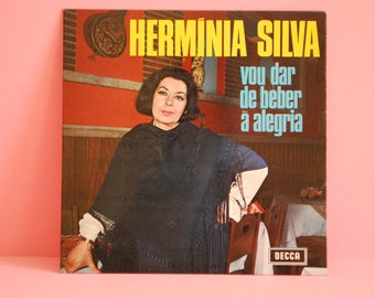 Puede incluir: Una portada de disco de vinilo vintage con una mujer con un chal negro, con el texto "HERMÍNIA SILVA vou dar de beber à alegria" y la etiqueta del disco "DECCA".