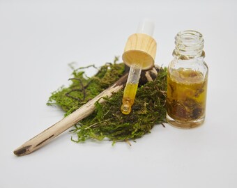 May include: A glass bottle with a dropper filled with a yellow liquid, a wooden stick, and green moss.