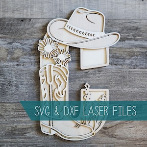 May include: A wooden cutout depicting a cowboy hat, a cowboy boot, and floral elements. The design includes the text "SVG & DXF LASER FILES" in a teal banner. The cutout is crafted from light-coloured wood.