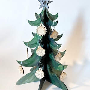 May include: A green wooden Christmas tree with a star on top and wooden ornaments with space-themed designs, including a sun, a planet, and a globe.