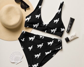 Op de afbeelding: Zwart-witte badpak met een kattenprint. De top is halter-stijl met een V-hals. De onderkant is een hoge taille bikini broek.