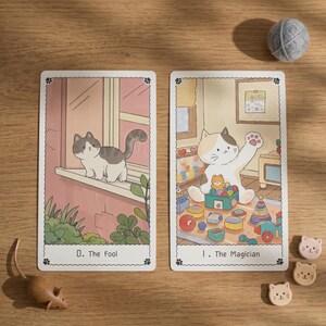 May include: Two rectangular tarot cards featuring cat illustrations. The left card shows a cat on a windowsill labeled 0. The fool. The right card shows a cat playing with toys labeled I. The Magician. Includes a wooden mouse and small cat-shaped tokens.