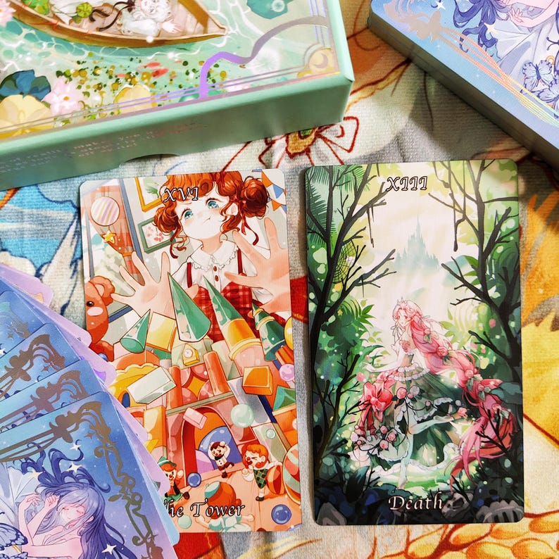 May include: Two tarot cards, one with a pink and green illustration of a woman in a forest with the text "Death" and the other with a colorful illustration of a girl surrounded by toys with the text "The Tower".