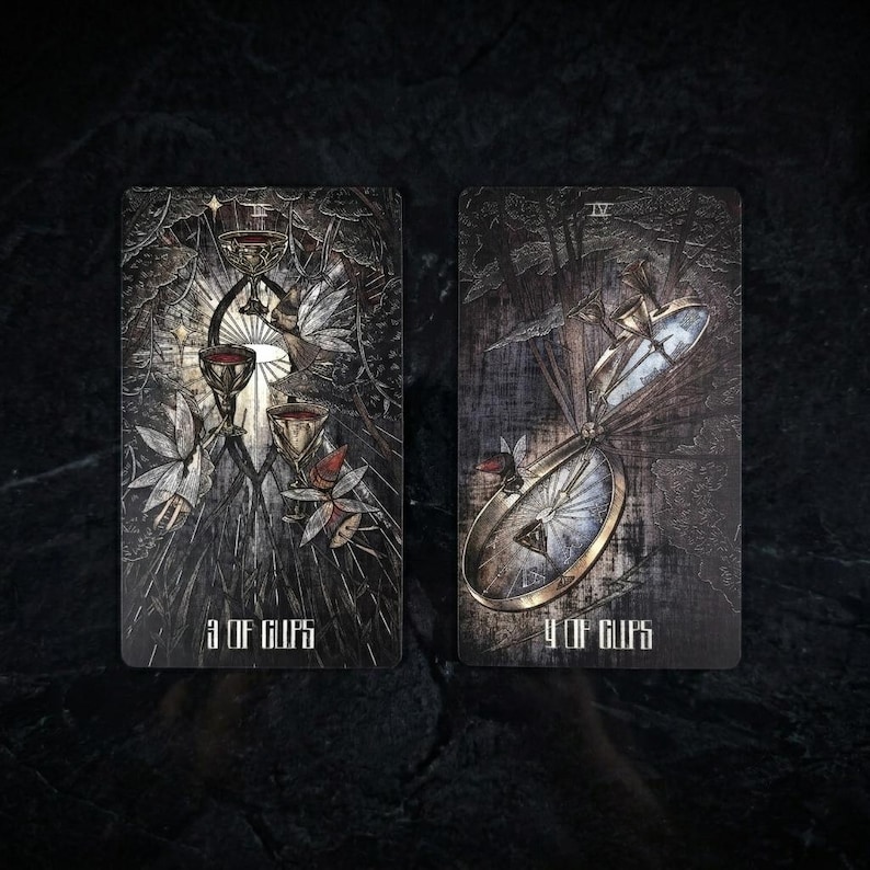 Op de afbeelding: Twee rechthoekige tarotkaarten met een donkere, getextureerde achtergrond. De linkerkaart, gelabeld 3 OF CUPS, toont drie versierde kelken en gevleugelde figuren. De rechterkaart, gelabeld 4 OF CUPS, bevat een groot, metalen kompasachtig object.