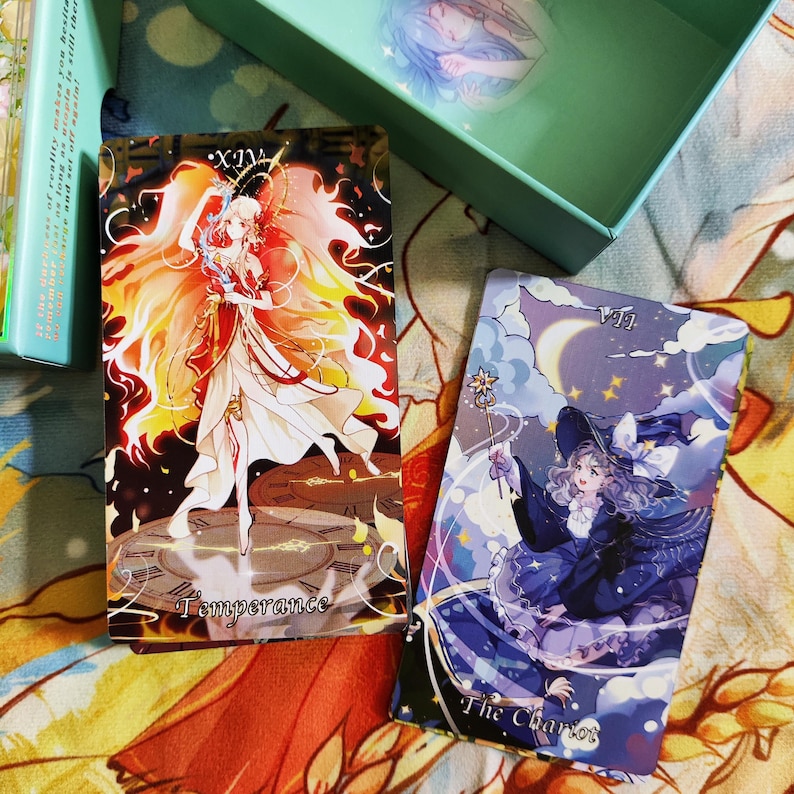 May include: Two tarot cards, one with a woman in a flowing white dress with orange flames around her, and the text "XIV Temperance". The other card features a woman in a blue dress and a witch's hat, with the text "VII The Chariot".