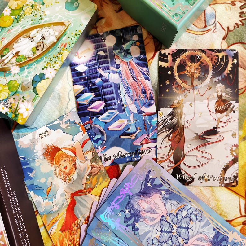 May include: A set of tarot cards with colorful illustrations featuring characters and symbols. The cards are arranged in a fan shape, with the top card showing a woman in a blue dress with a red hat, standing on a staircase made of books. The text on the card reads "The Hierophant". The card below it shows a woman in a white dress with a red hat, standing in a field of wheat. The text on the card reads "11". The card below that shows a woman in a blue dress with a red hat, standing in a field of wheat. The text on the card reads "Wheel of Fortune".