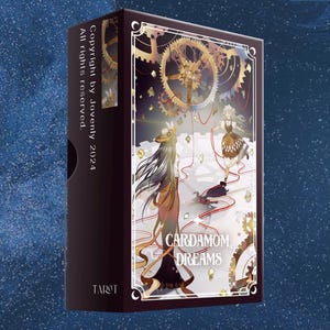 May include: A box of Cardamom Dreams Tarot cards featuring a colorful illustration of two women in a whimsical setting with gears and a red string connecting them. The box is black with gold lettering and the text "Copyright by Jovenly 2024 All rights reserved" on the side.