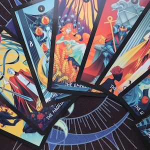 K&ouml;nnte beinhalten: Eine Tarotkarten-Auslage mit bunten Illustrationen und schwarzen R&auml;ndern. Die Karten beinhalten Der Magier, Die Kaiserin, Der Wagen, Die Hohepriesterin, Der Stern und Der Turm.