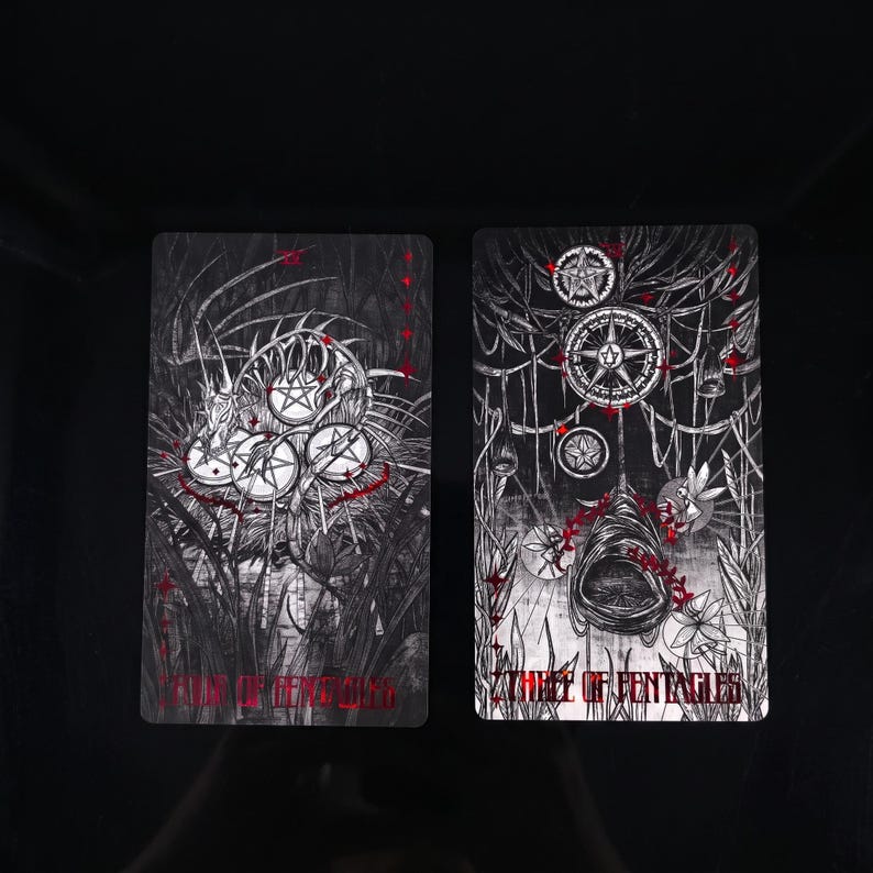 Op de afbeelding: Twee rechthoekige tarotkaarten met ingewikkelde zwart-witte lijntekeningen met rode accenten. De linkerkaart toont de tekst 'KING OF PENTACLES' en de rechterkaart toont de tekst 'THREE OF PENTACLES' met gedetailleerde illustraties van munten.