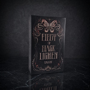 Op de afbeelding: Een rechthoekige tarotkaartendoos in zwart met koperkleurige letters die Elegy of Black Lichen Tarot spellen. De voorkant bevat een gedetailleerde illustratie van een vlinder omringd door doornige wijnstokken en gebladerte in kopertinten.