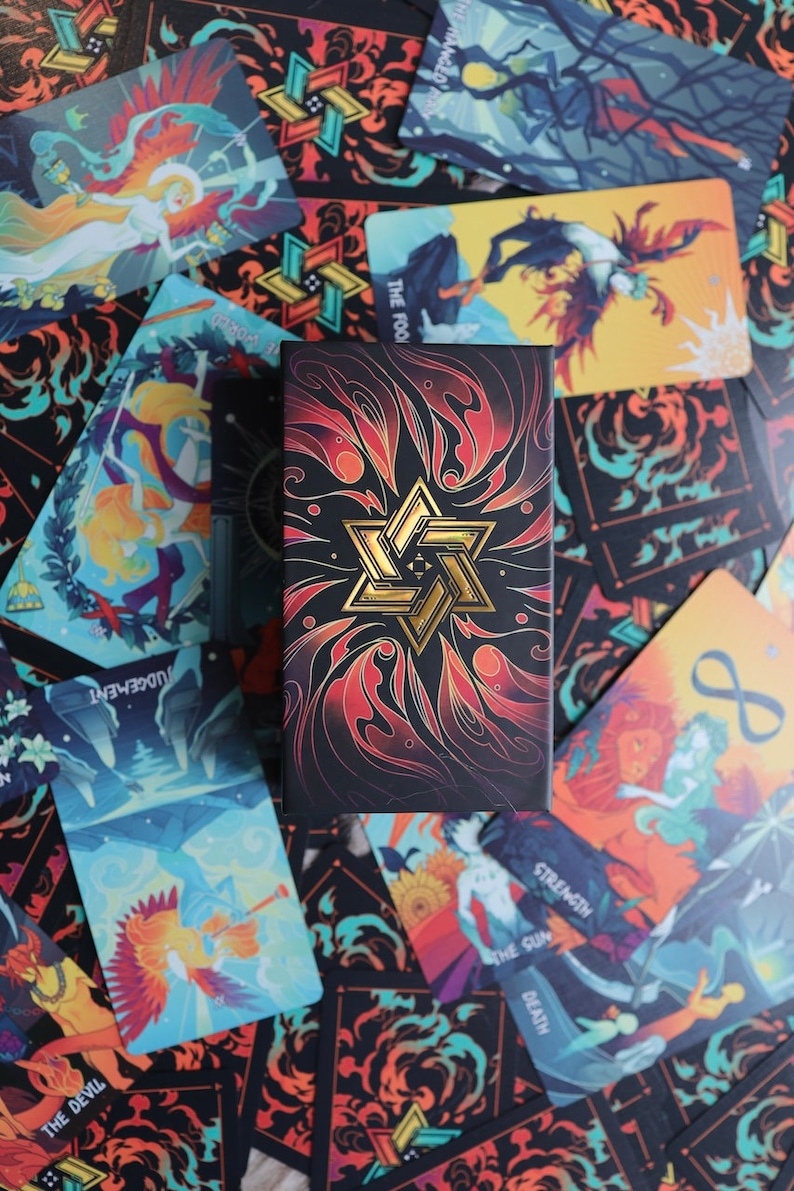 K&ouml;nnte beinhalten: Ein Tarotkartenspiel mit einer schwarzen und goldenen Schachtel. Die Schachtel hat ein goldenes Sternendesign auf einem roten und schwarzen Hintergrund. Die Karten sind um die Schachtel herum verstreut und zeigen verschiedene Bilder von Menschen und Tieren.