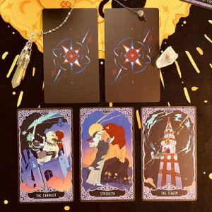 Op de afbeelding: Vijf tarotkaarten met paarse randen en illustraties. De kaarten zijn "De Wagen", "Kracht", "De Toren" en twee blanco kaarten met een stervormig ontwerp.