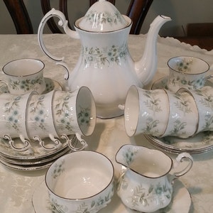 Peut inclure: Un service à thé blanc avec un motif floral. L'ensemble comprend une théière, un pot à crème, un sucrier et six tasses et soucoupes.