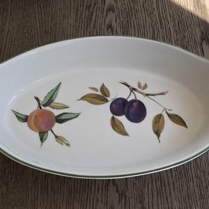 May include: White oval baking dish with a green rim and a floral design featuring plums and peaches.